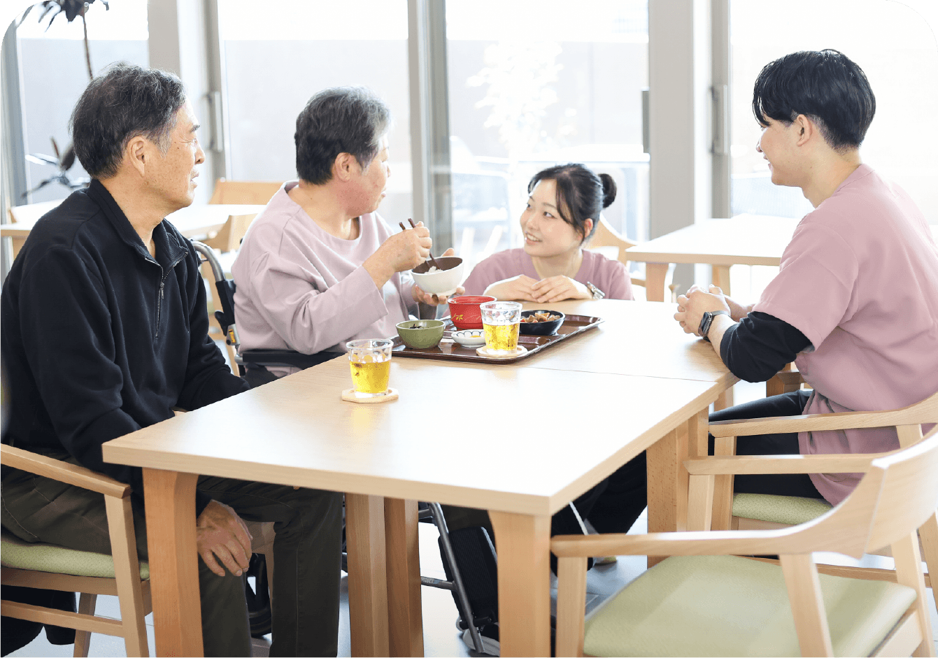 ダイニングルームで入居者の方々とスタッフが食事や会話を楽しんでいる様子