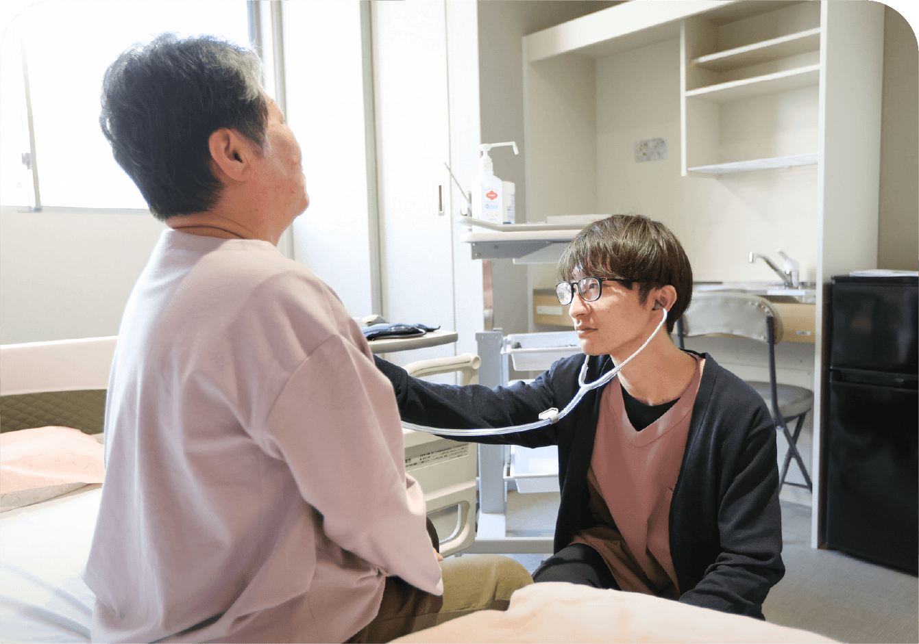 スタッフが聴診器で入居者の体調を確認している様子